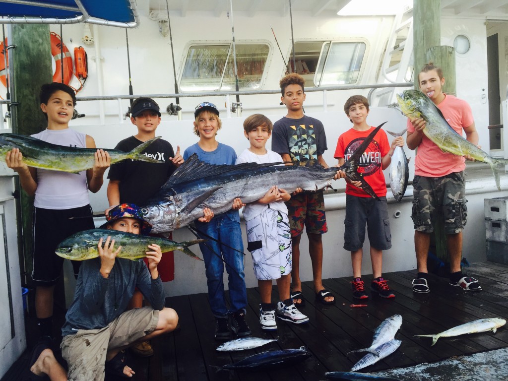 Kids holding sailfish and dolphin at the dock