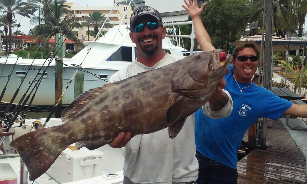 Capt Rod and Mick posing with a black grouper at the marina.