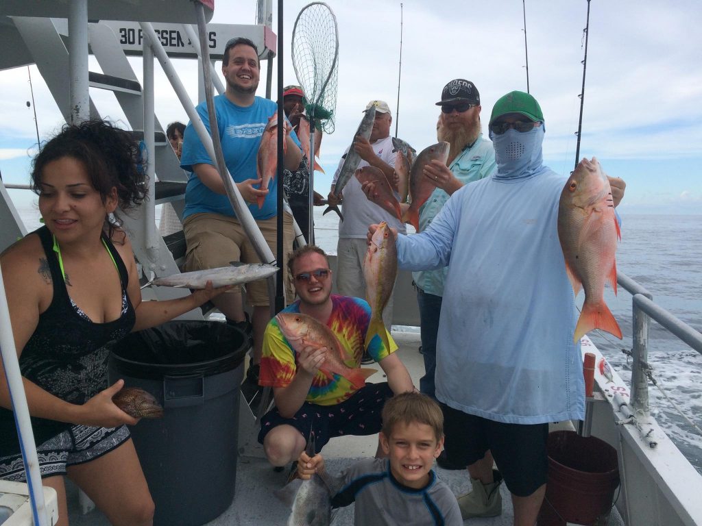 Happy anglers holding a nice catch of snappers caught drift fishing aboard the Catch My Drift