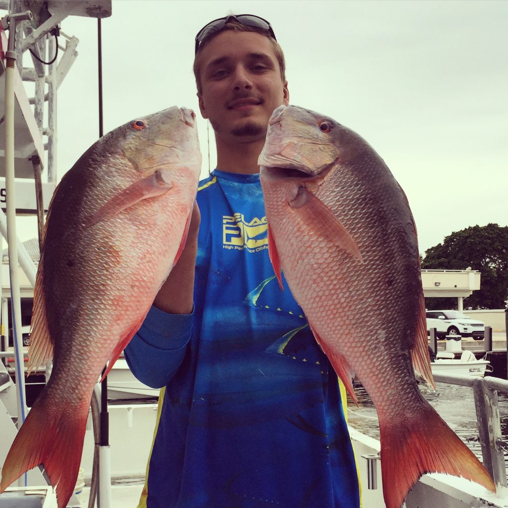 Alex holding a pair of mutton snappers aboard the Catch My Drift.