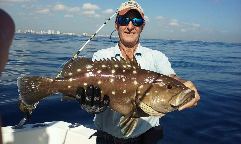 Guy holding a nice looking snowy grouper just landed off the coast of Fort Lauderdale
