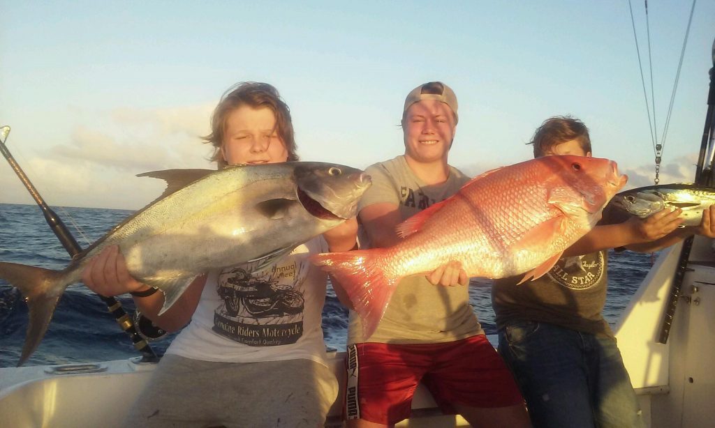 Guys holding their catch of a big almaco jack and huge red snapper (and a bonito) on the boat