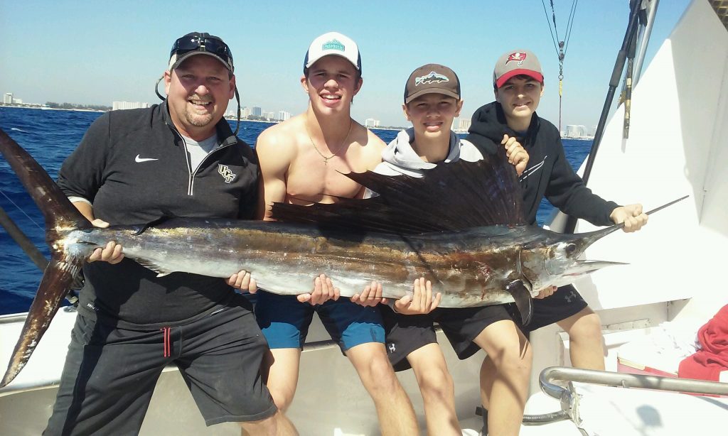 Big sailfish being held by family.