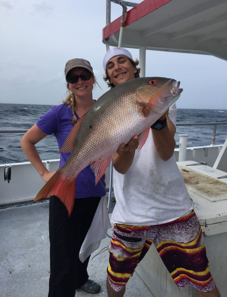Kyle holding a big mutton snapper next to the lady angler who caught it, aboard the Catch My Drift.