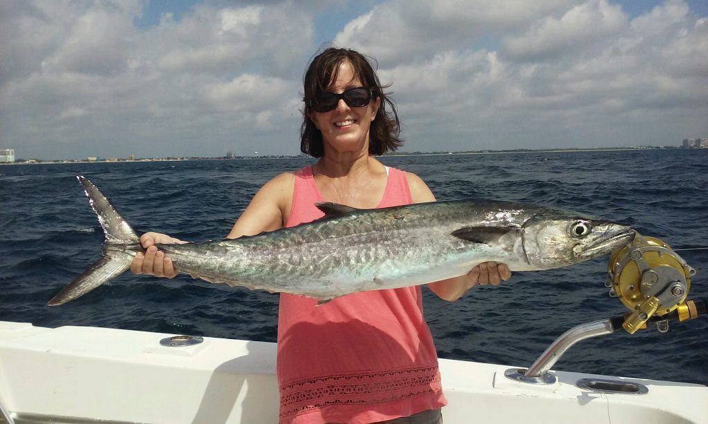 Lady holding a big kingfish she just caught.