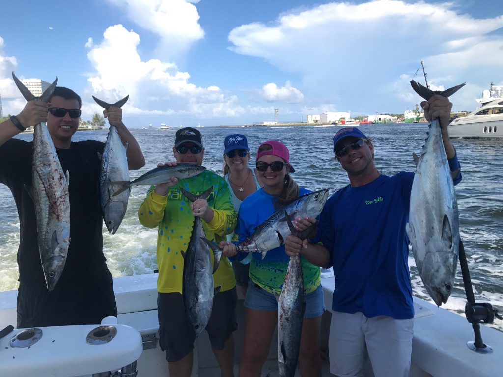 Group holding a bunch of bonitos and kingfish