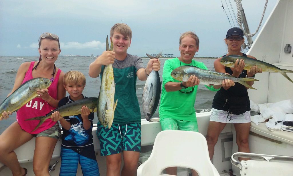 Family holding their fish up out at sea, bunch of dolphin and tunas.