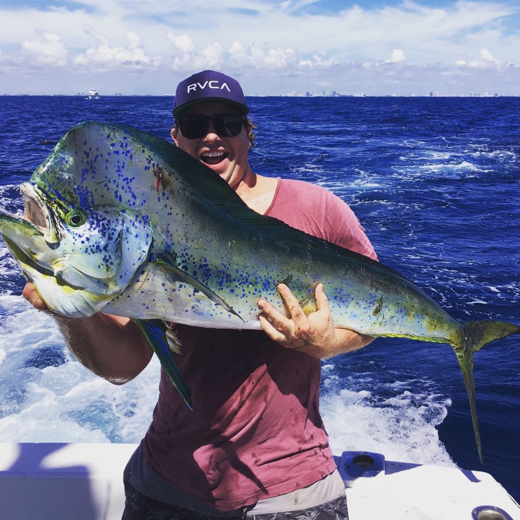 Guy holding an all lit up mahi-mahi dolphin he just caught.