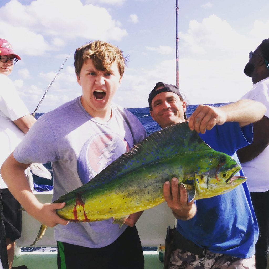 Angler making a funny expression as he poses with a dolphin he just caught on the drift boat trip.