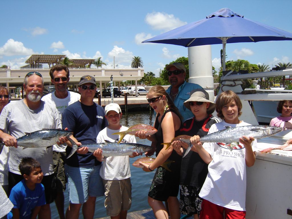 Anglers after their deep sea fishing trip holding their catch at the dock.