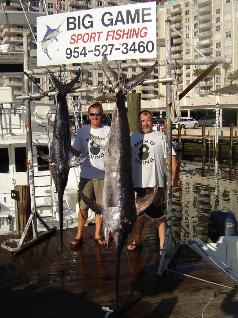 Guys posing with two swordfish they just caught on a night swordfishing charter