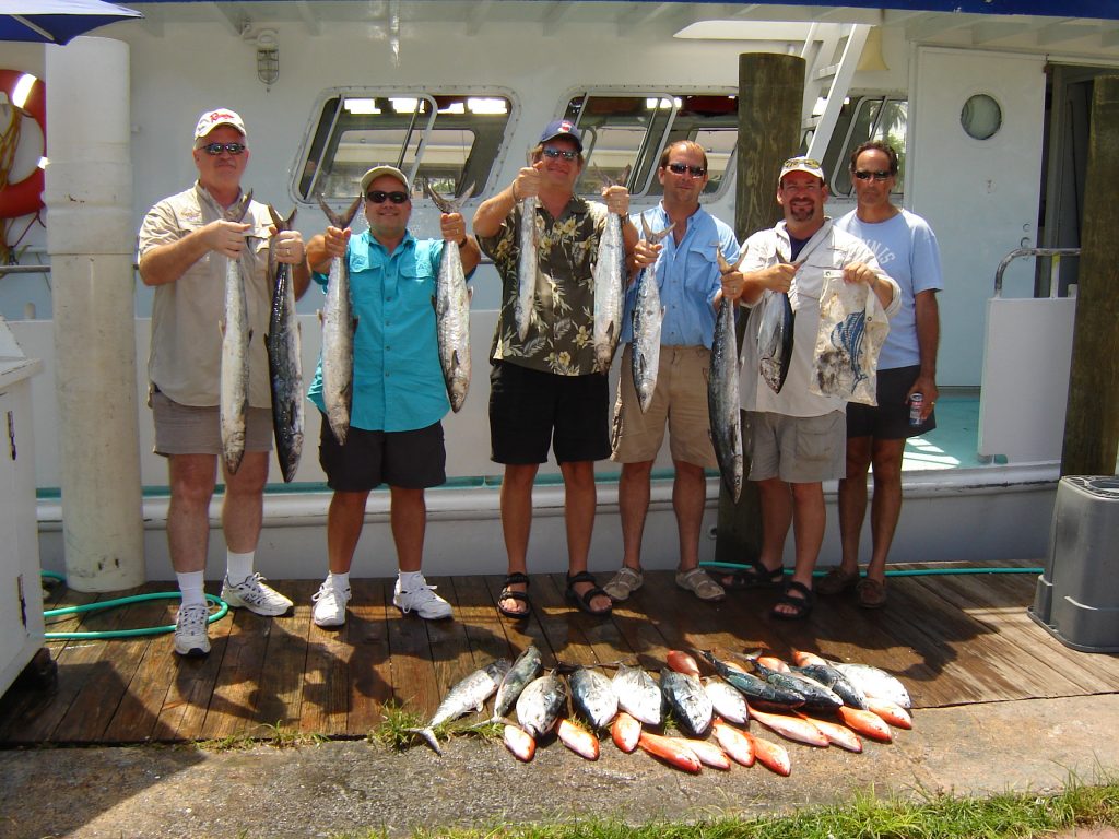 Group posing with their catch in front of the boat, lots of fish.