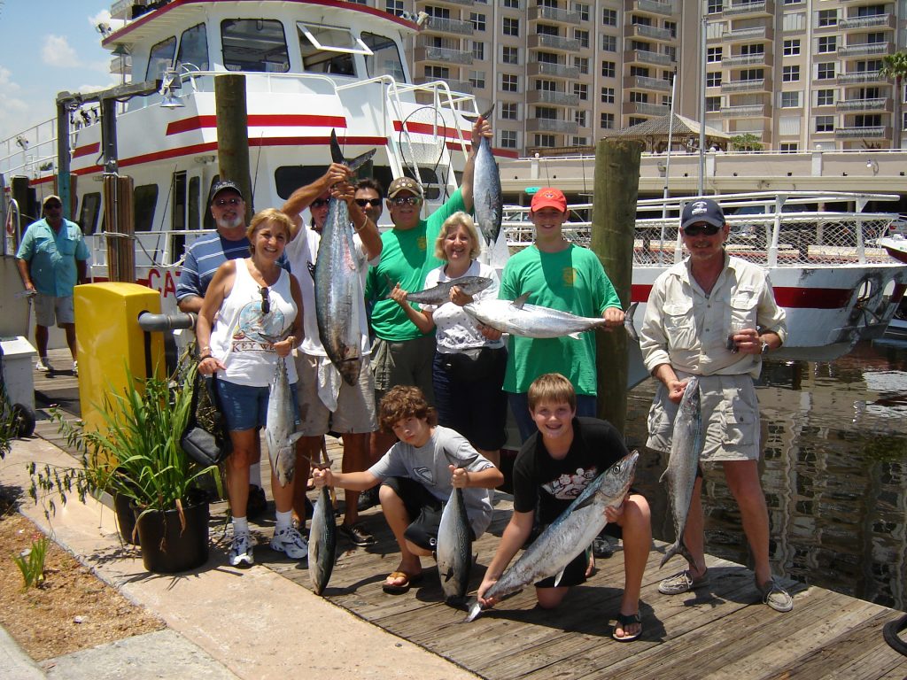 Group holding up their catch at the dock in front of the boat. lots of kingfish and a few bonitos.