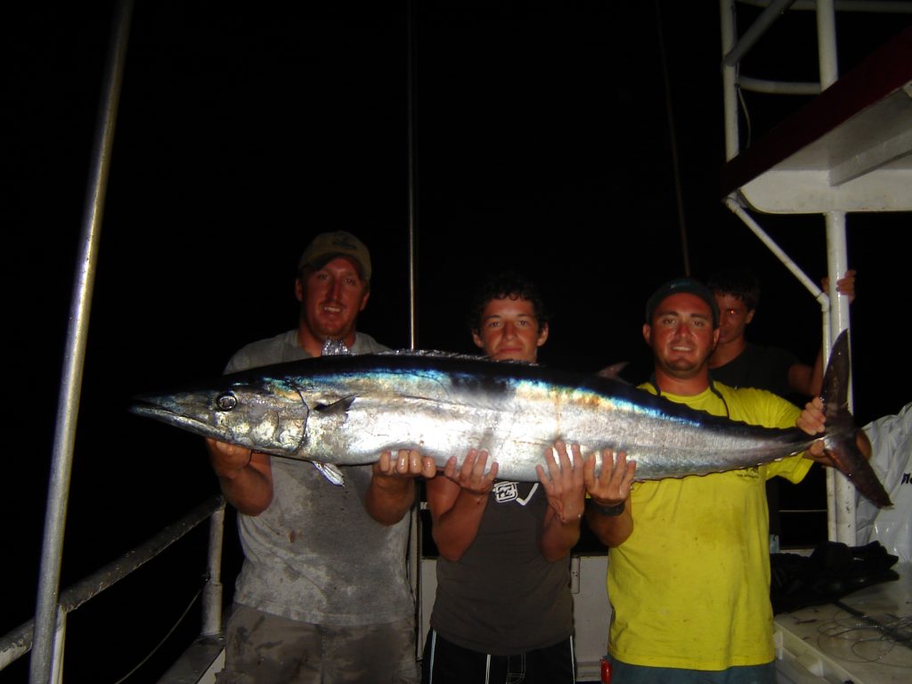 The guys holding the big wahoo we just caught while we were fishing for swordfish at night.