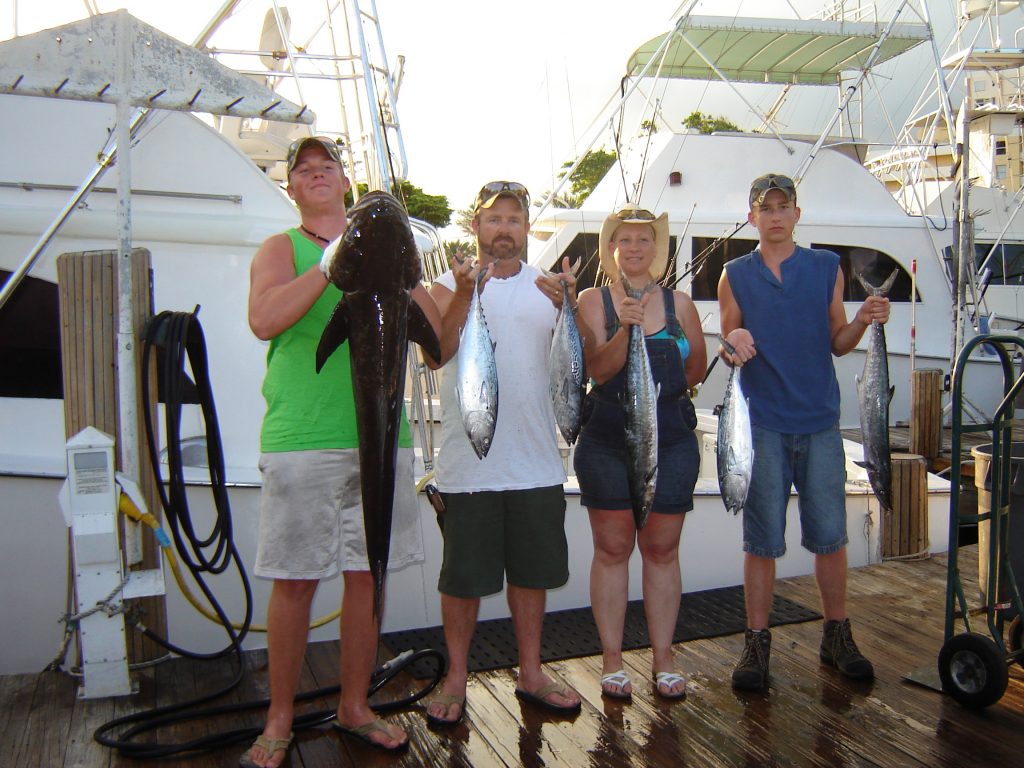 Family holding up their fish after their fishing trip, one guy holding a 5ft cobia