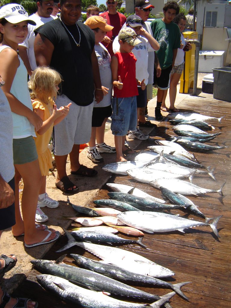 Group of folks, fresh off our party boat trip admiring their catch of fish laid out on the dock.