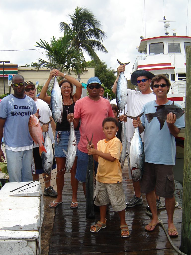 Happy customers holding up their catch in front of our drift fishing boat.