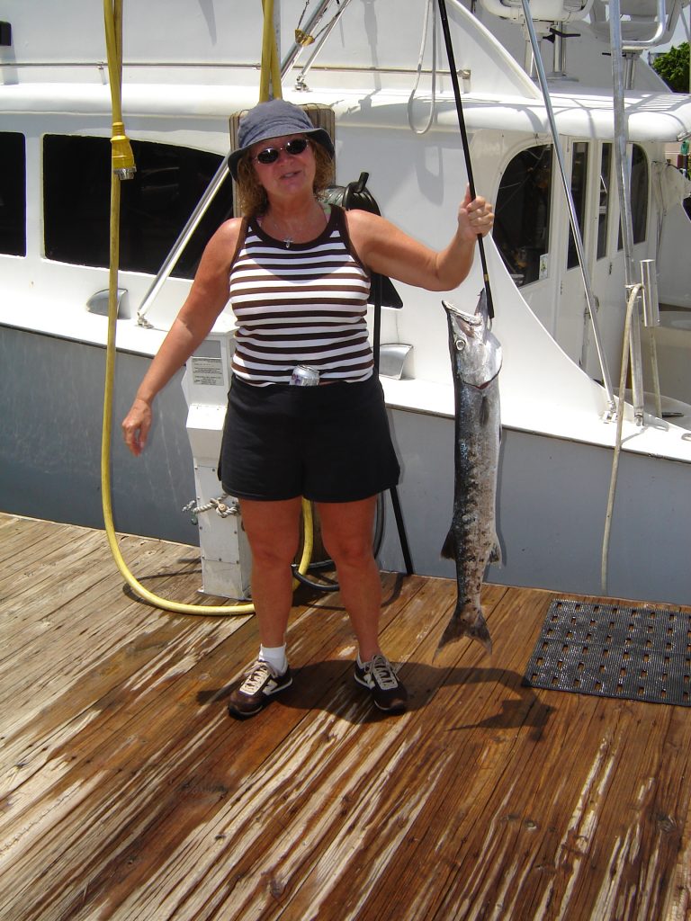 lady holding a barracuda she just caught on an inshore fishing trip