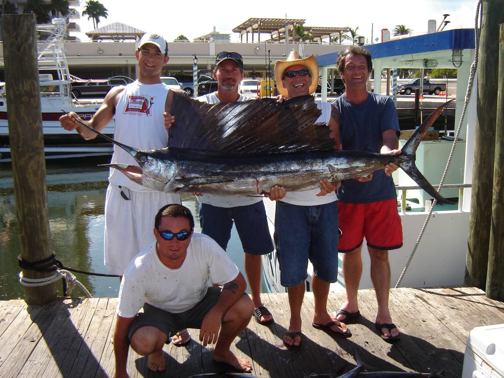bachelor party group posing with a sailfish they just caught on their big group charter