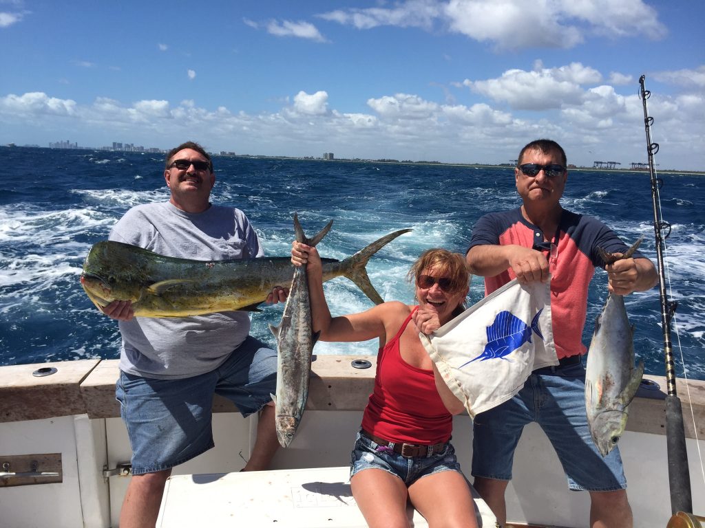 Lucky anglers holding up their great catch of dolphin, kingfish, tuna and sailfish release flag