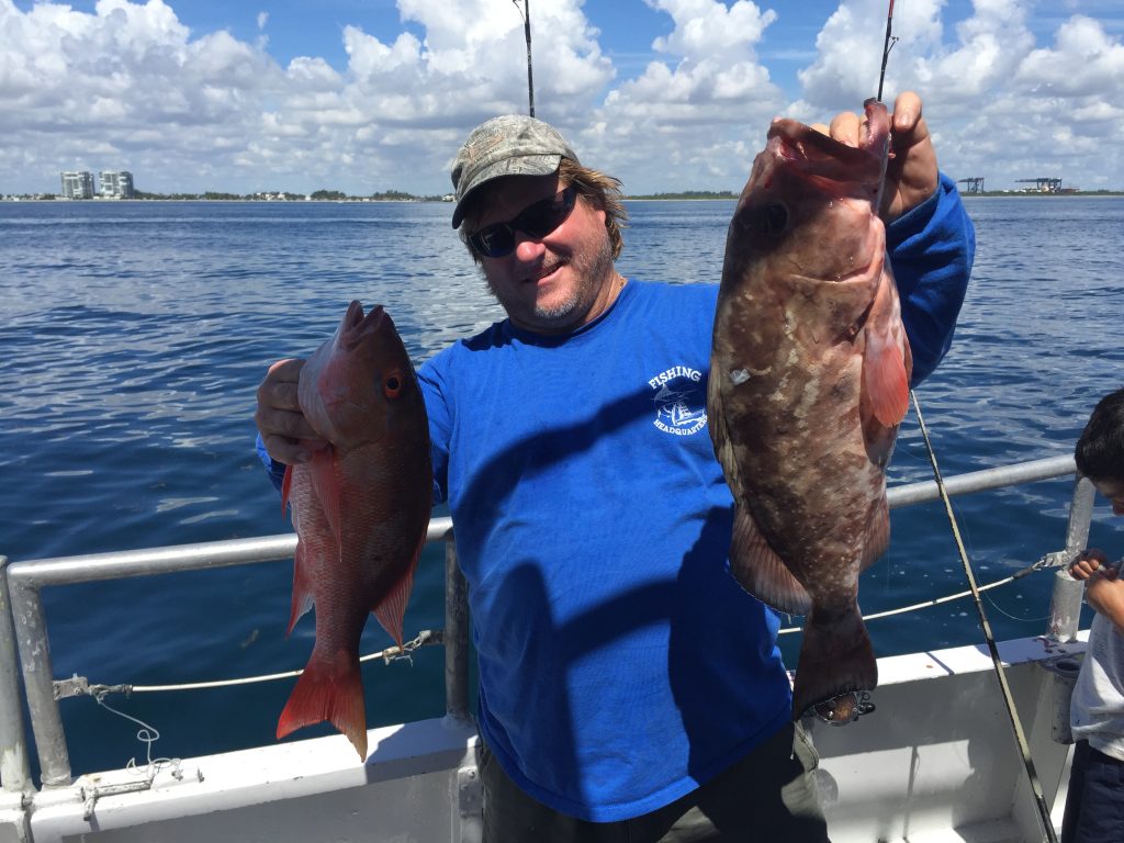 Capt Billy holding a mutton and grouper aboard the Catch My Drift