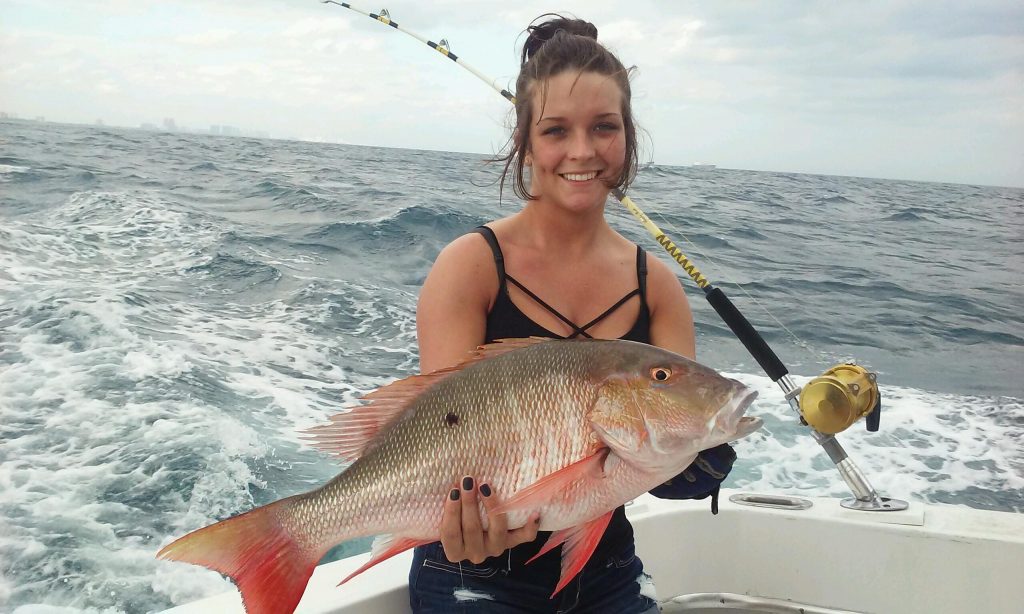 Pretty girl holding a big mutton snapper she just caught on our fishing charter.