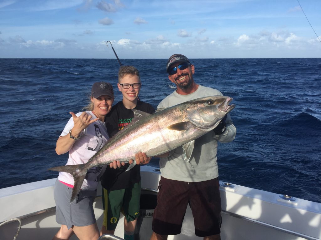 Couple people holding a big amberjack on their charter