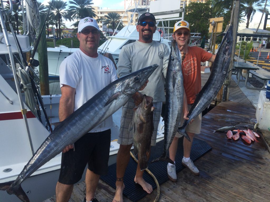 Happy customers holding a few big wahoo and other fish at the end of their fishing trip