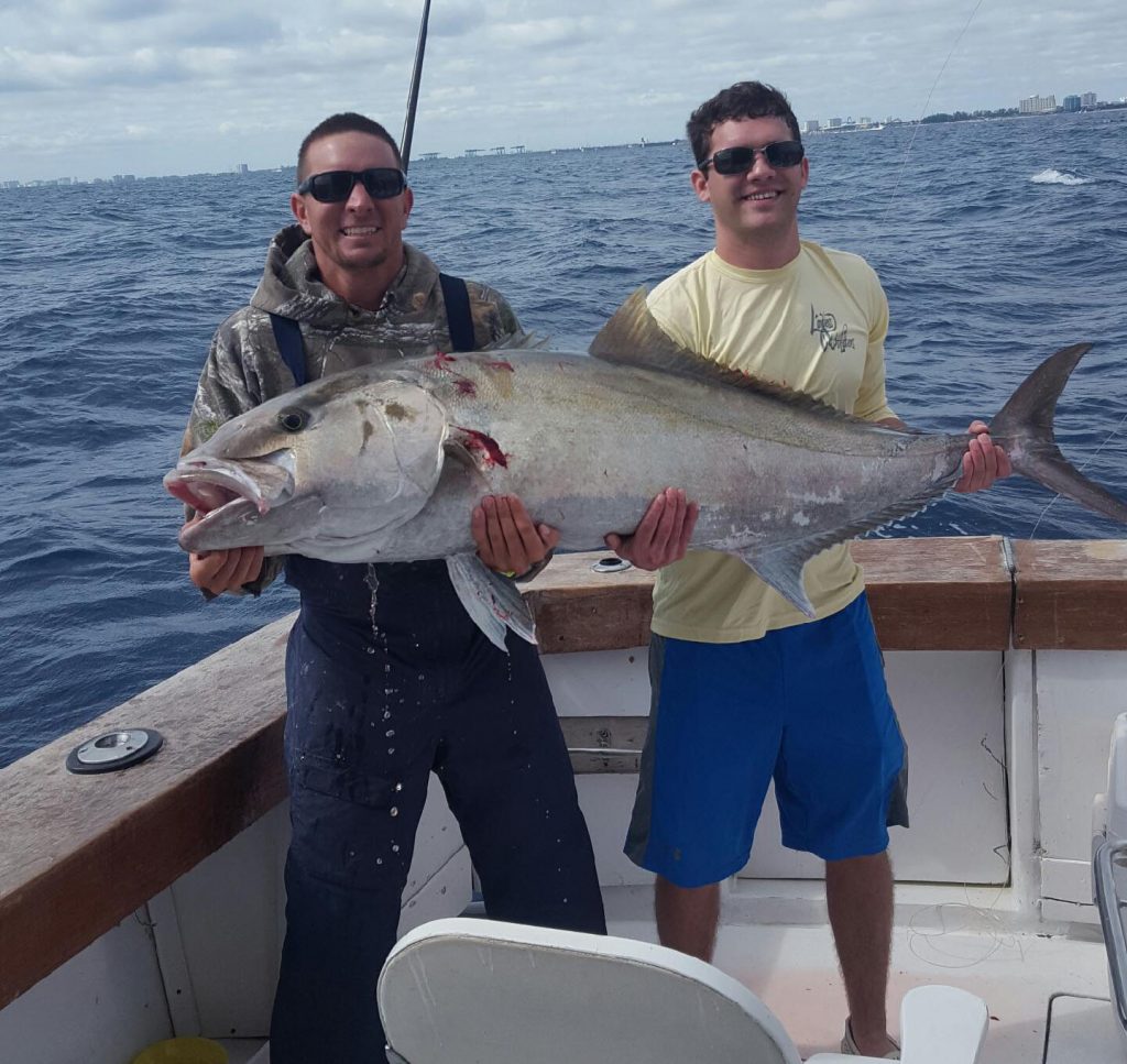 2 guys holding a beast of an amberjack just caught.