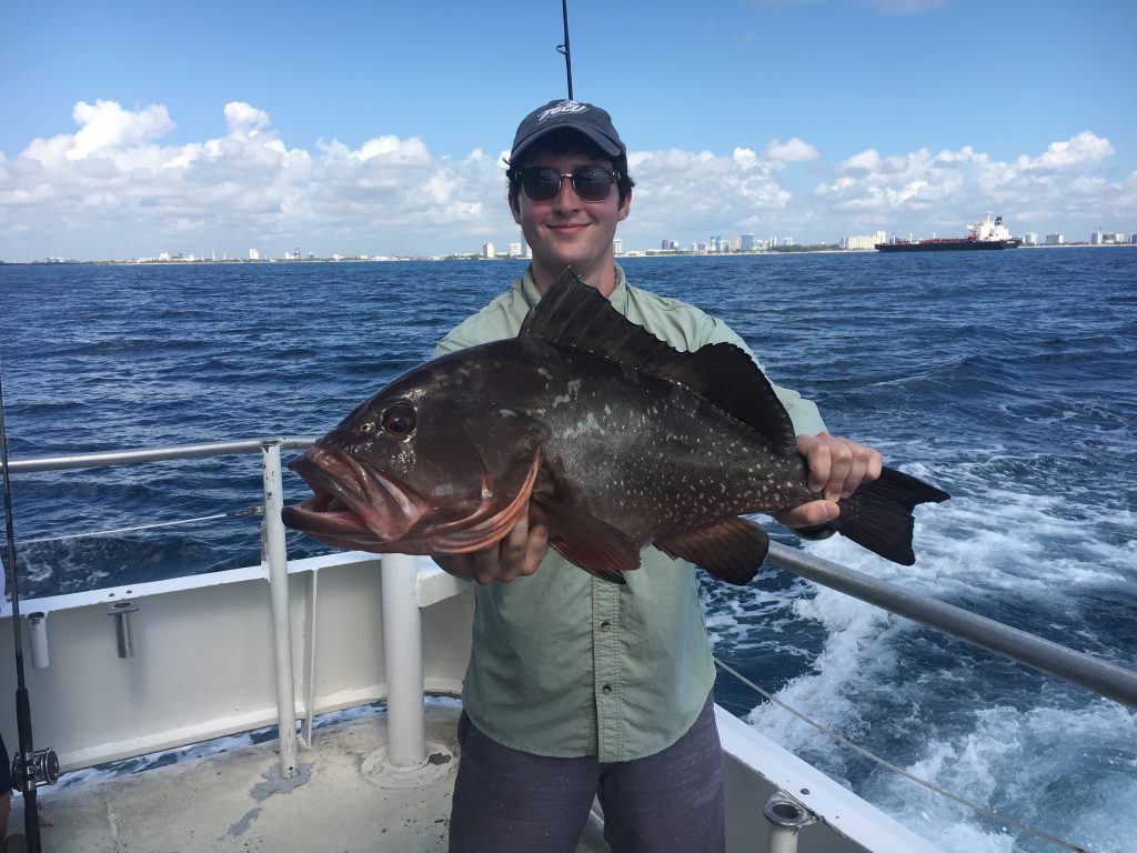 Lucky angler holding his nice red grouper on the back of the drift boat.