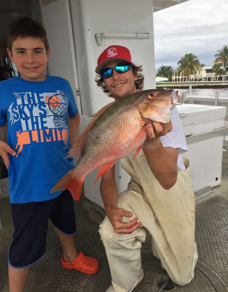 Kyle holding a mutton snapper next to the kid that caught him aboard the Mary B III drift fishing boat.