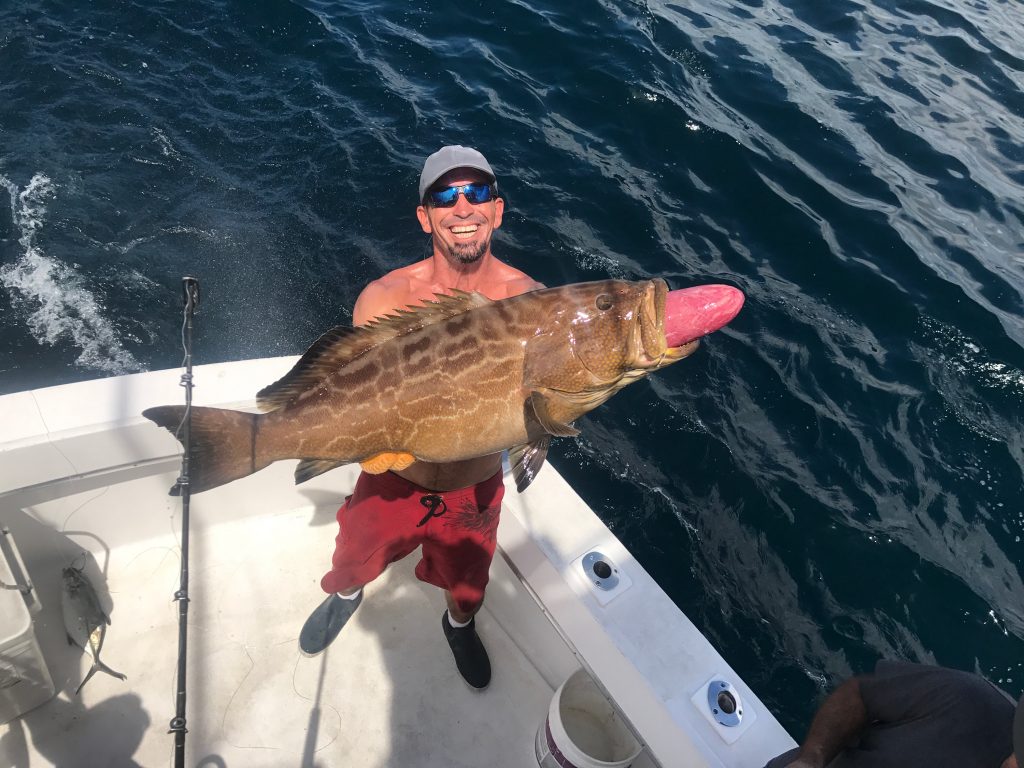 Big black grouper being held by Mick on the boat.
