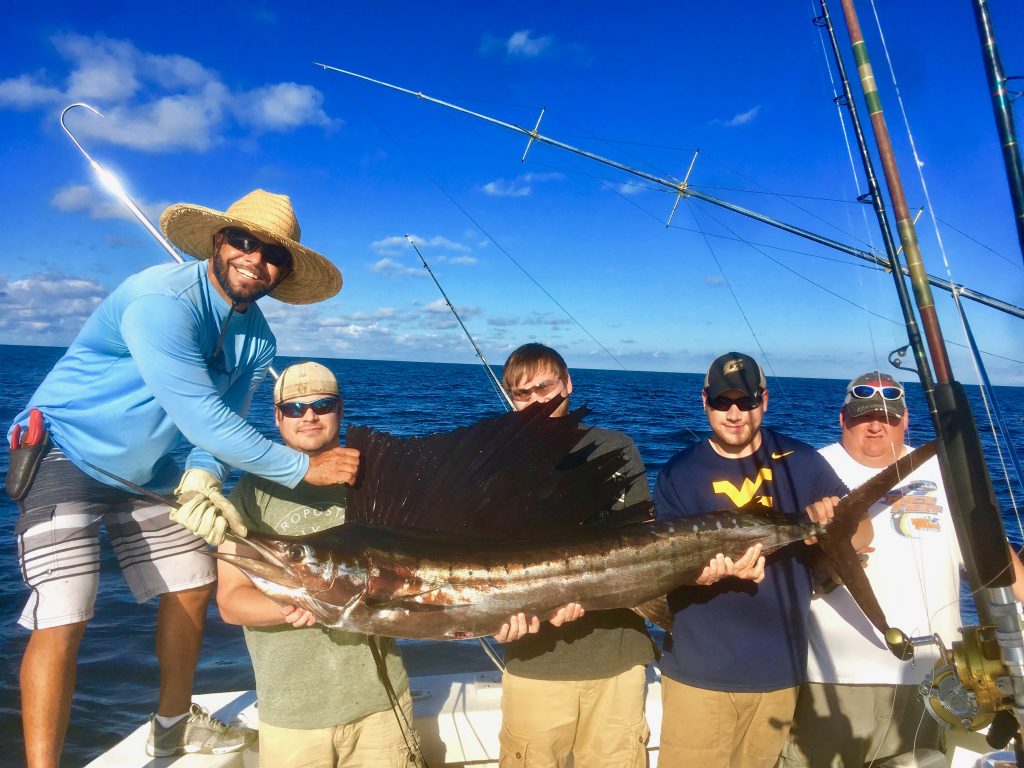 4 buddies along with Capt. Bobby pose with their sailfish they just caught on their bachelor party fishing trip.