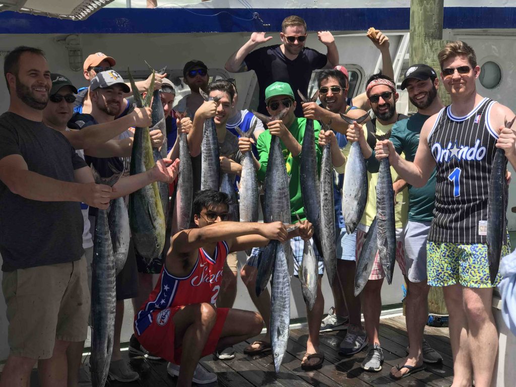 Group of guys on a bachelor party fishing charter holding up their catch of 11 wahoo, some mahi-mahi and tunas.