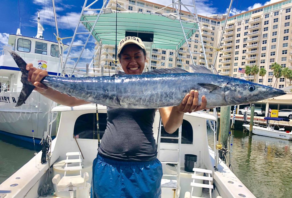 Girl at the dock holding up a wahoo she caught during her Ft Lauderdale fishing charter.