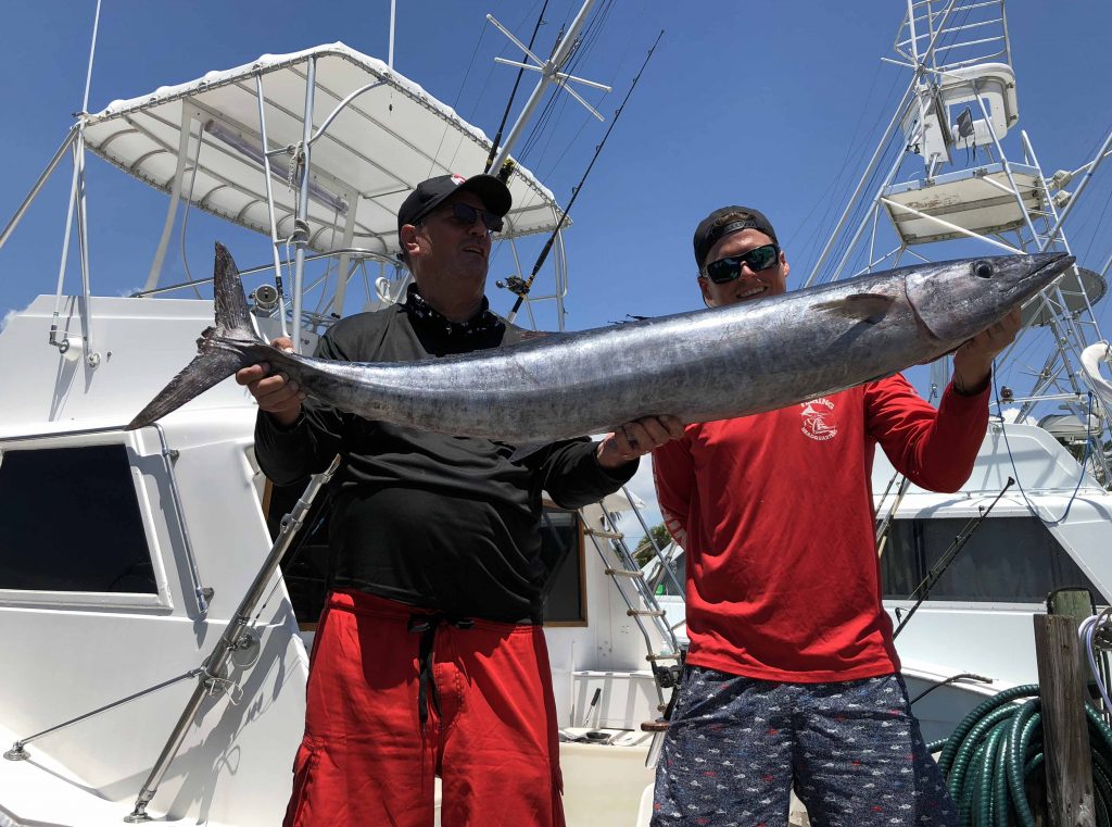 2 guys holding up a big wahoo at the dock in Fort Lauderdale.