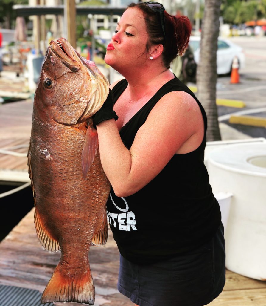 A fisher gal holding up the Cubera Snapper about to give it a big kiss.