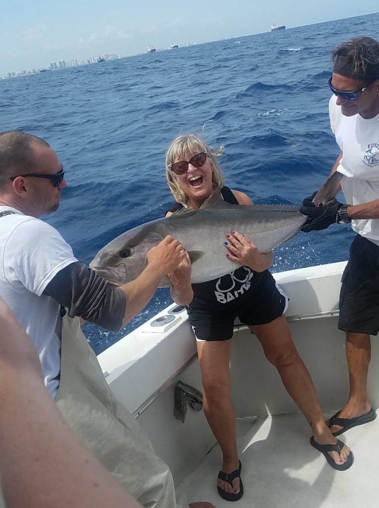 A very happy gal holding a 40 pound amberjack during her deep sea fishing charter