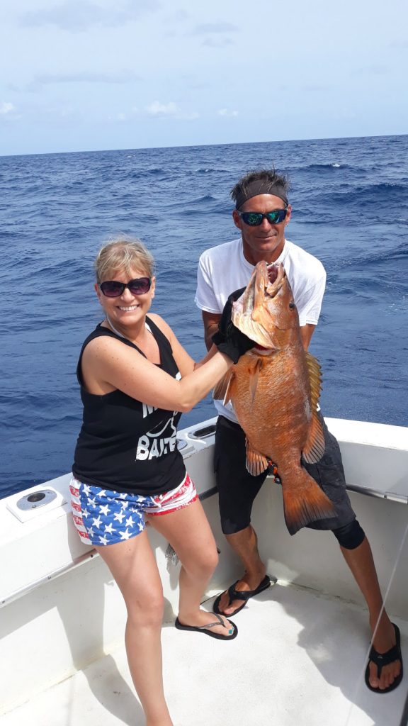 Awesome catch of a Cubera Snapper.  Dave helping the lady angler hold it up at sea.