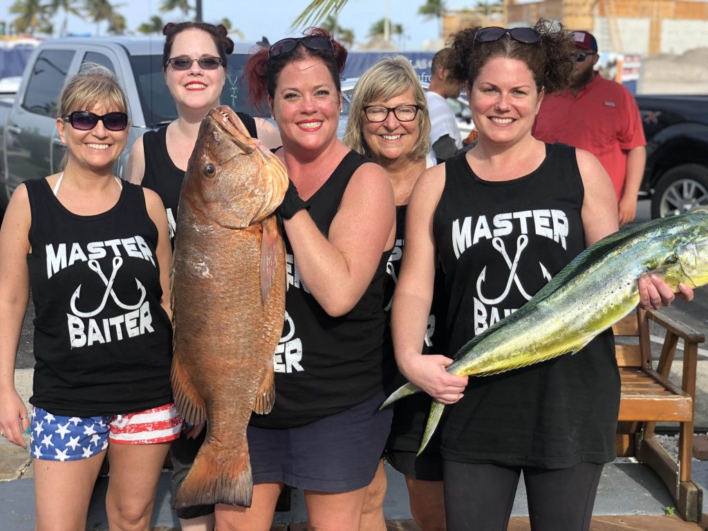 Master Baiter Girls holding up the amberjack and the Cubera Snapper at the dock.